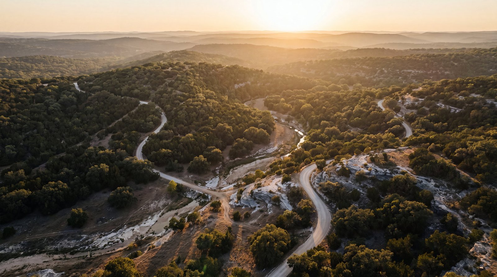 Rolling limestone ridgelines and a ranch road in the Texas Hill Country at golden hour
